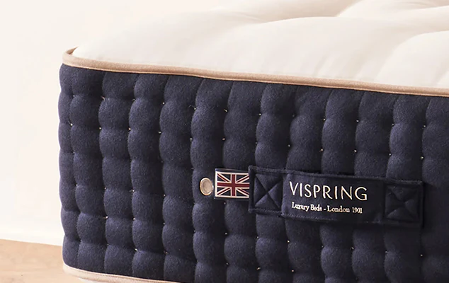 Vispring mattress showing its quilted fabric design, Union Jack detail, and premium handcrafted construction on side panel.