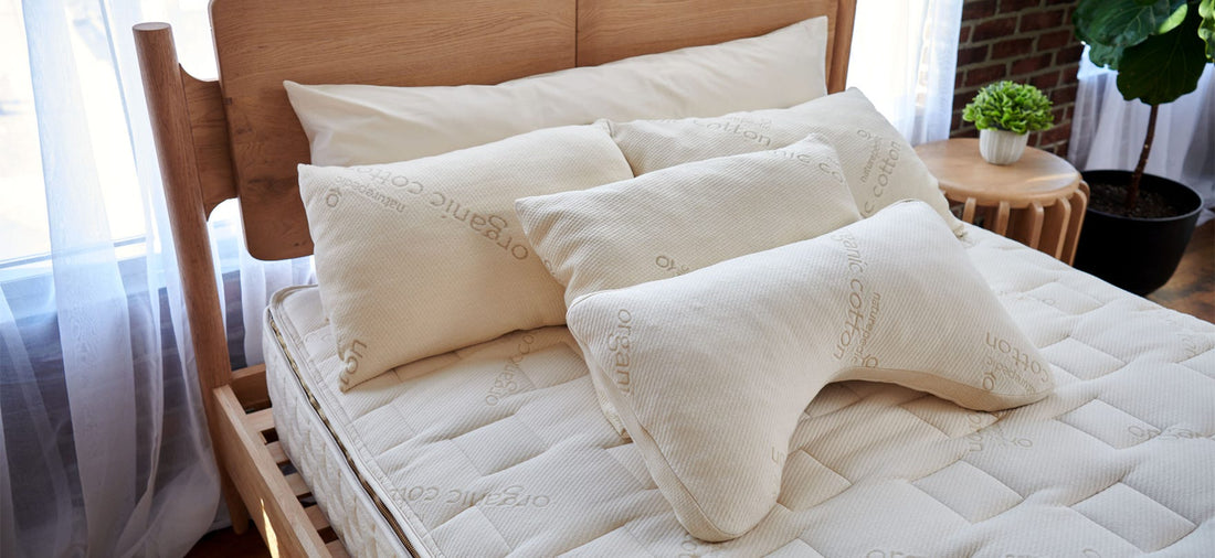 Quilted Naturepedic organic cotton mattress topped with multiple pillows, including a contoured cervical support pillow.